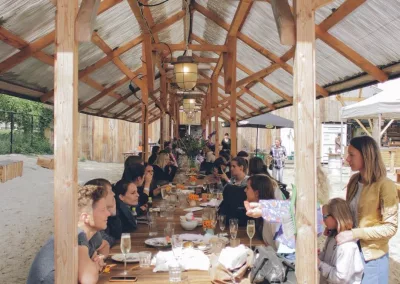 lange houten tafel vol mensen die samen eten