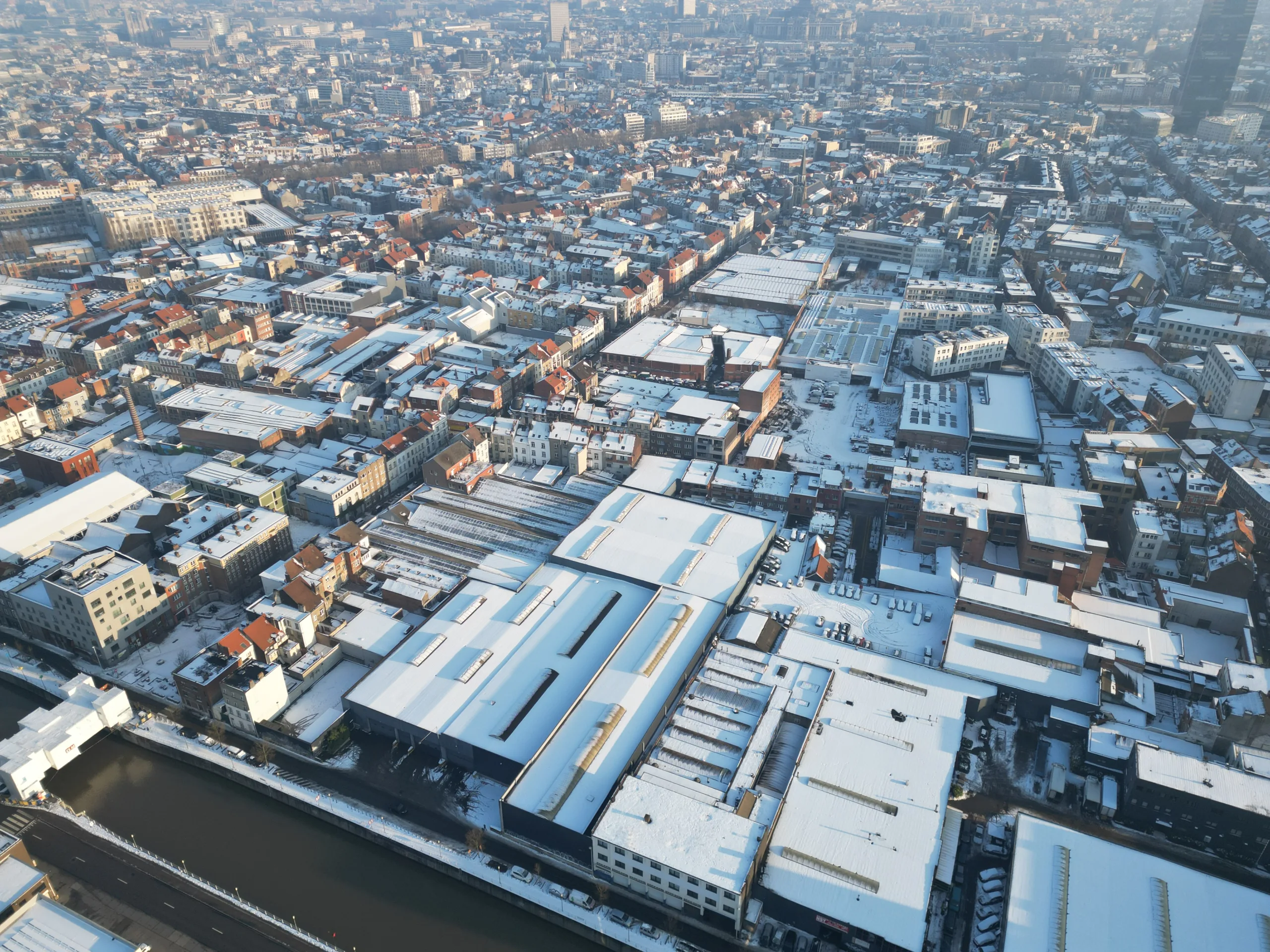 Een luchtfoto van een industriegebied langs het kanaal, gelegen in het hartje van Molenbeek. Talloze fabrieken en bedrijven strekken zich uit langs de waterweg, waar bedrijvigheid en handel samenkomen in deze levendige buurt
